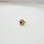 Close-up of tiny floral 18K nose pin gold on a clean white surface displaying its detailed carving

