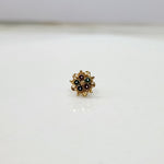 Front view of floral gold nose pin with green stones on a clean white surface