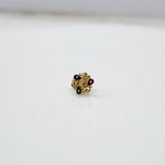 Close-up of tiny floral 18K nose pin gold on a clean white background showing fine craftsmanship