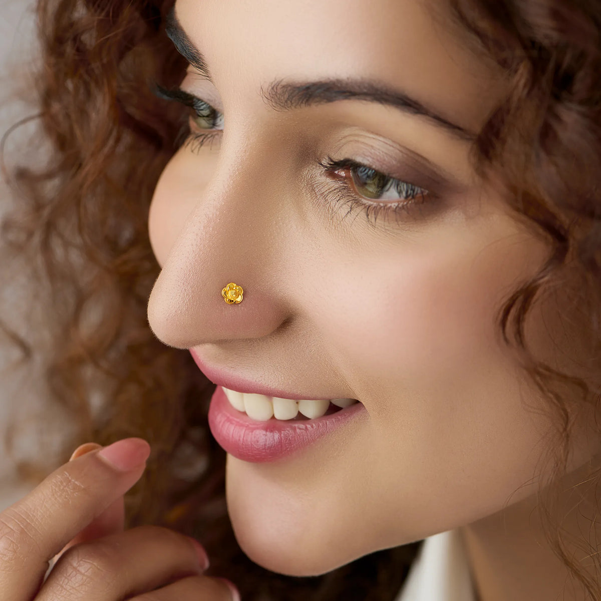 Woman wearing a small floral gold nose pin showing a graceful everyday look from a side angle