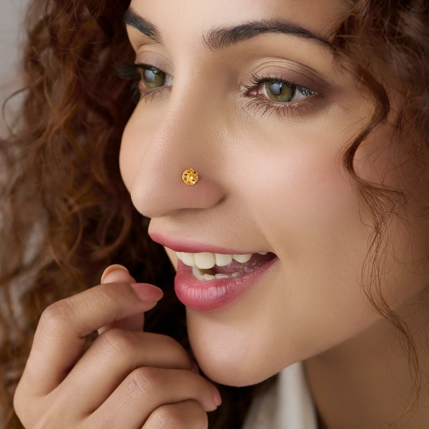 Woman wearing an elegant 18K gold nose pin highlighting a delicate floral design for a graceful everyday look