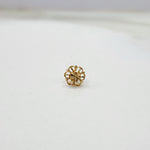 Close-up of small 18K nose pin gold on a marble surface showing its intricate flower-inspired design