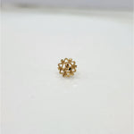 Close-up of small 18K nose pin gold on a marble-like surface showing its detailed flower-inspired design