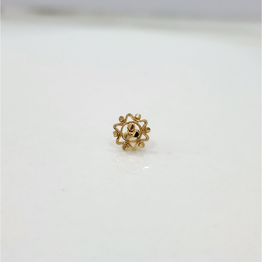 Close-up of small 18K nose pin gold on a marble-like surface showing its detailed flower-inspired design