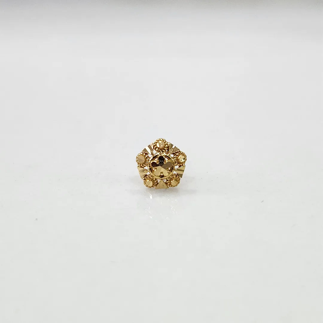 Close-up of a small 18K nose pin gold on a light background showing intricate carved detailing