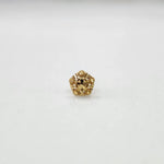 Close-up of a small 18K nose pin gold on a light background showing intricate carved detailing