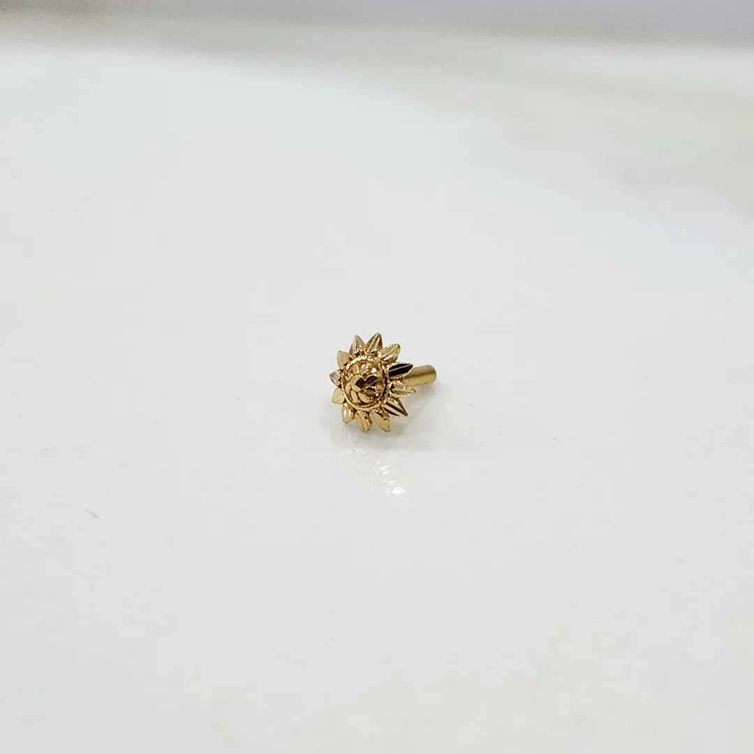 Tiny sun motif 18K nose pin gold on a white surface highlighting its delicate finish
