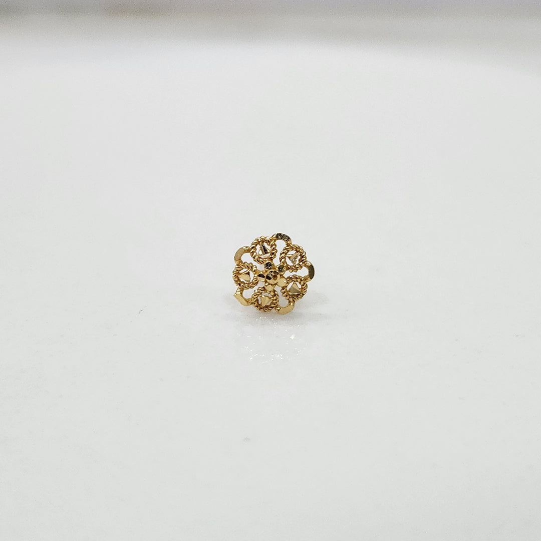 Slight side angled view of floral gold nose pin on a white surface emphasizing its neat finish and craftsmanship