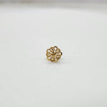 Slight side angled view of floral gold nose pin on a white surface emphasizing its neat finish and craftsmanship