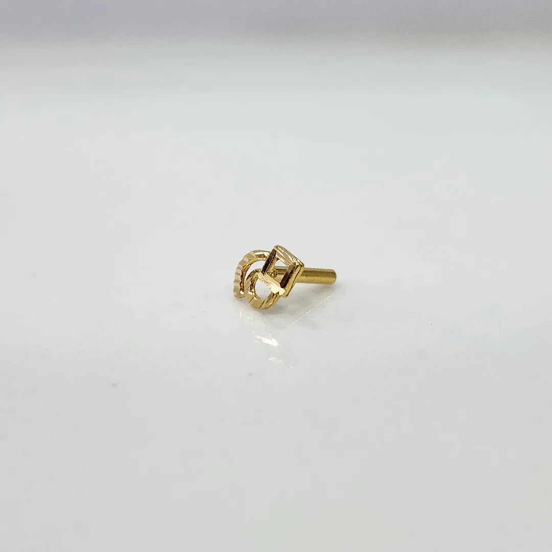Tiny geometric 18K nose pin gold on a white surface showing its delicate handcrafted detailing
