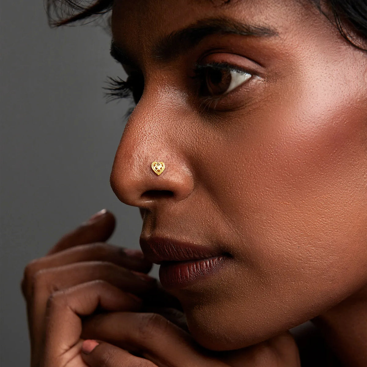 Woman wearing an elegant 18K heart gold nose pin highlighting a minimal and sophisticated look