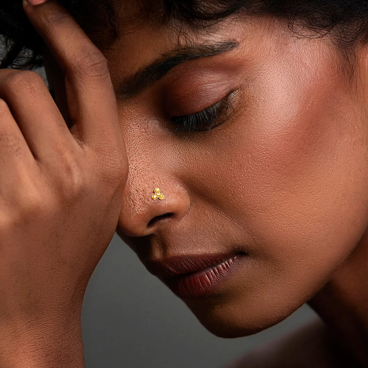 Woman wearing a minimalist 18K nose pin gold in a soft side profile showcasing an elegant and modern everyday look