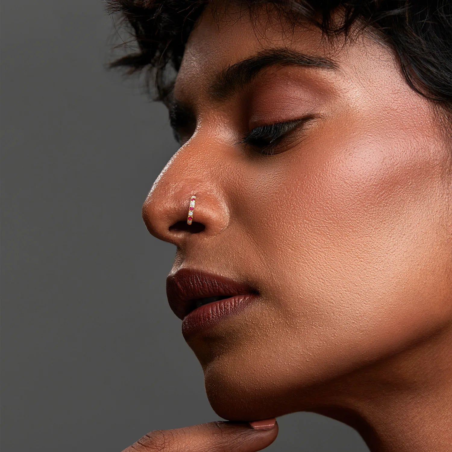 Side profile of a woman wearing a gemstone gold nose ring highlighting refined everyday styling