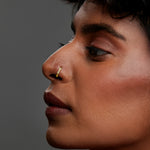 Side profile of a woman wearing a small 18K gold nose ring demonstrating subtle everyday elegance