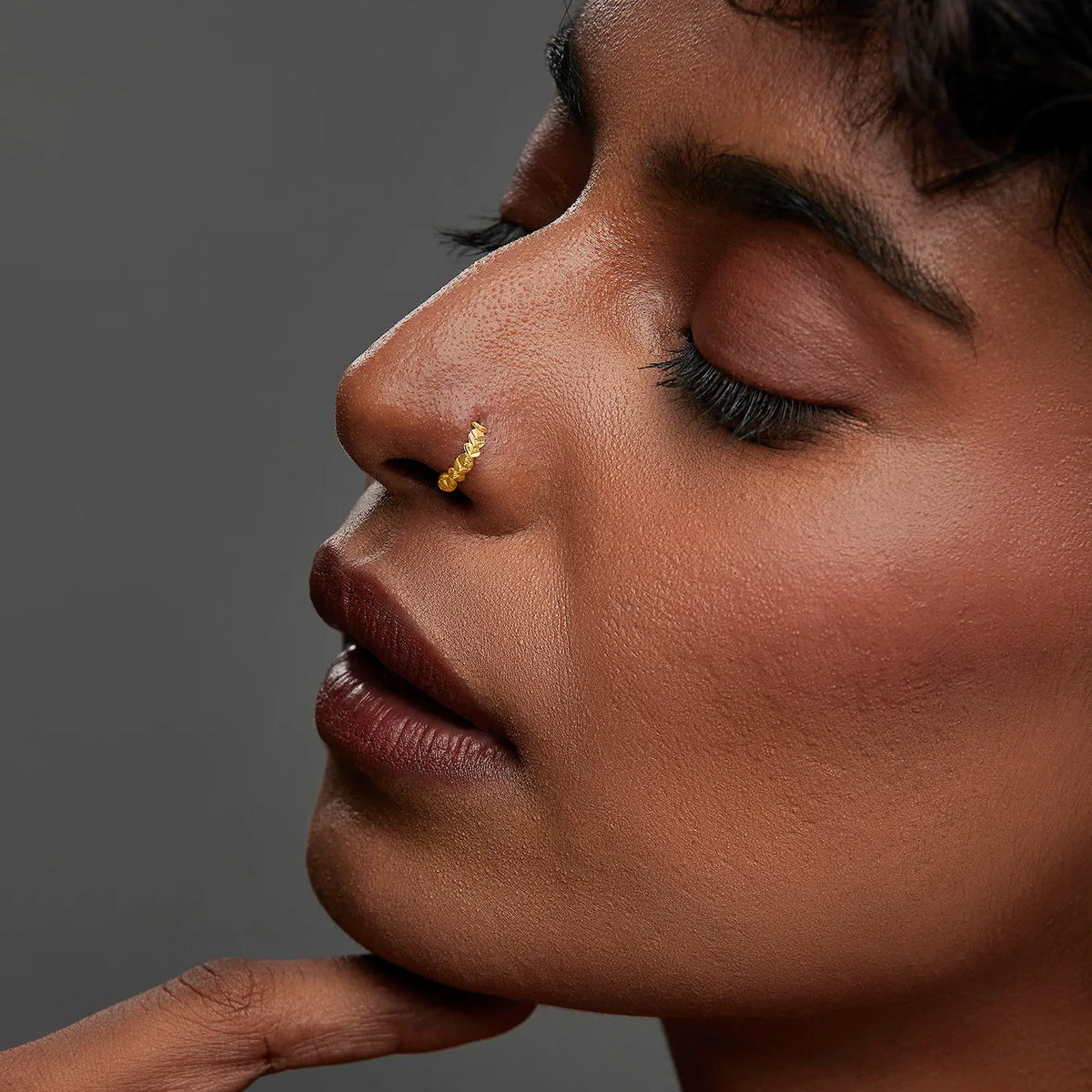 Woman wearing a leaf design gold nose ring shown in a close up profile highlighting elegant styling