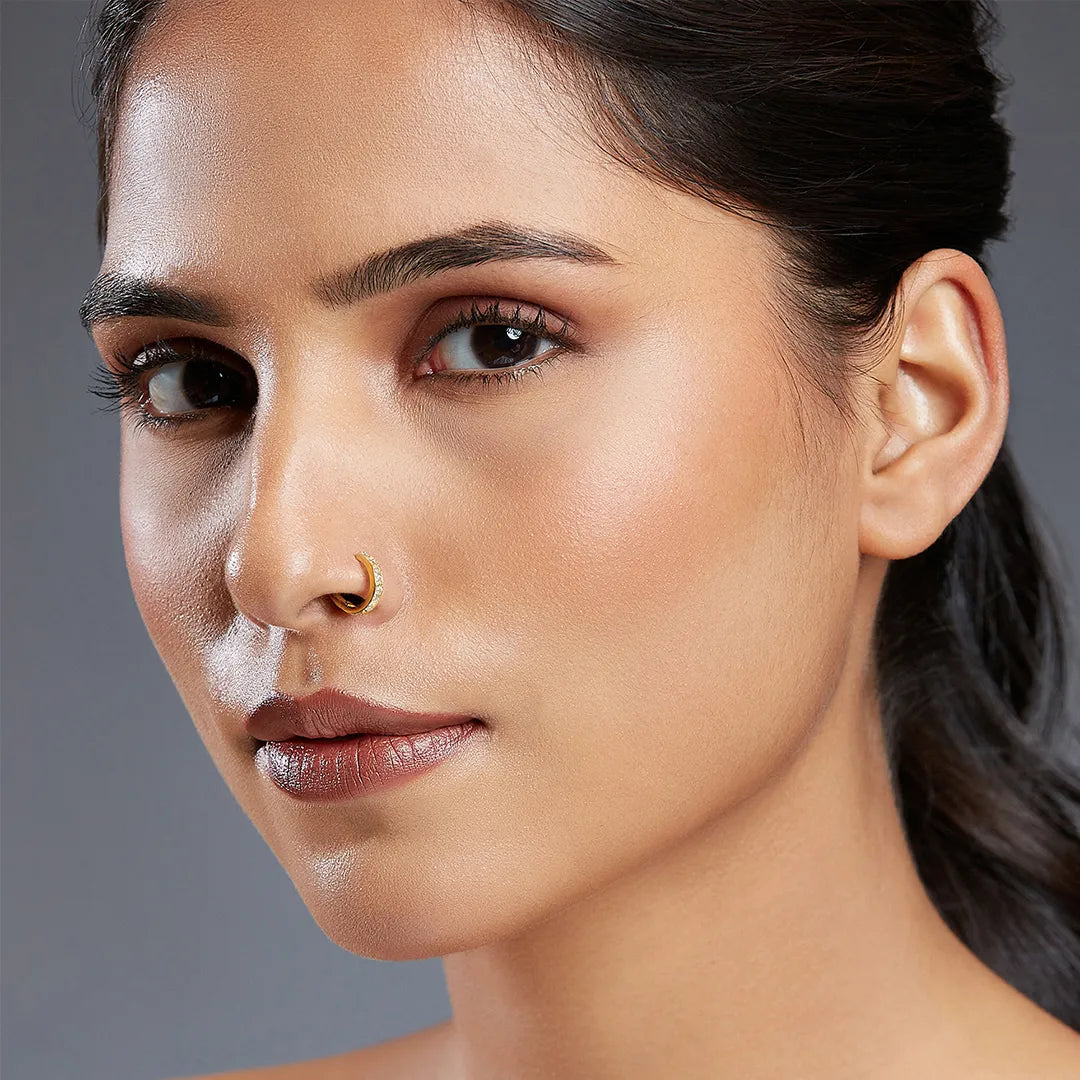 Front portrait of a woman wearing a delicate gemstone gold nose ring for minimal styling