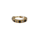 Vertical close up of stone studded 18K gold hoop nose ring on a white background highlighting its sleek circular design