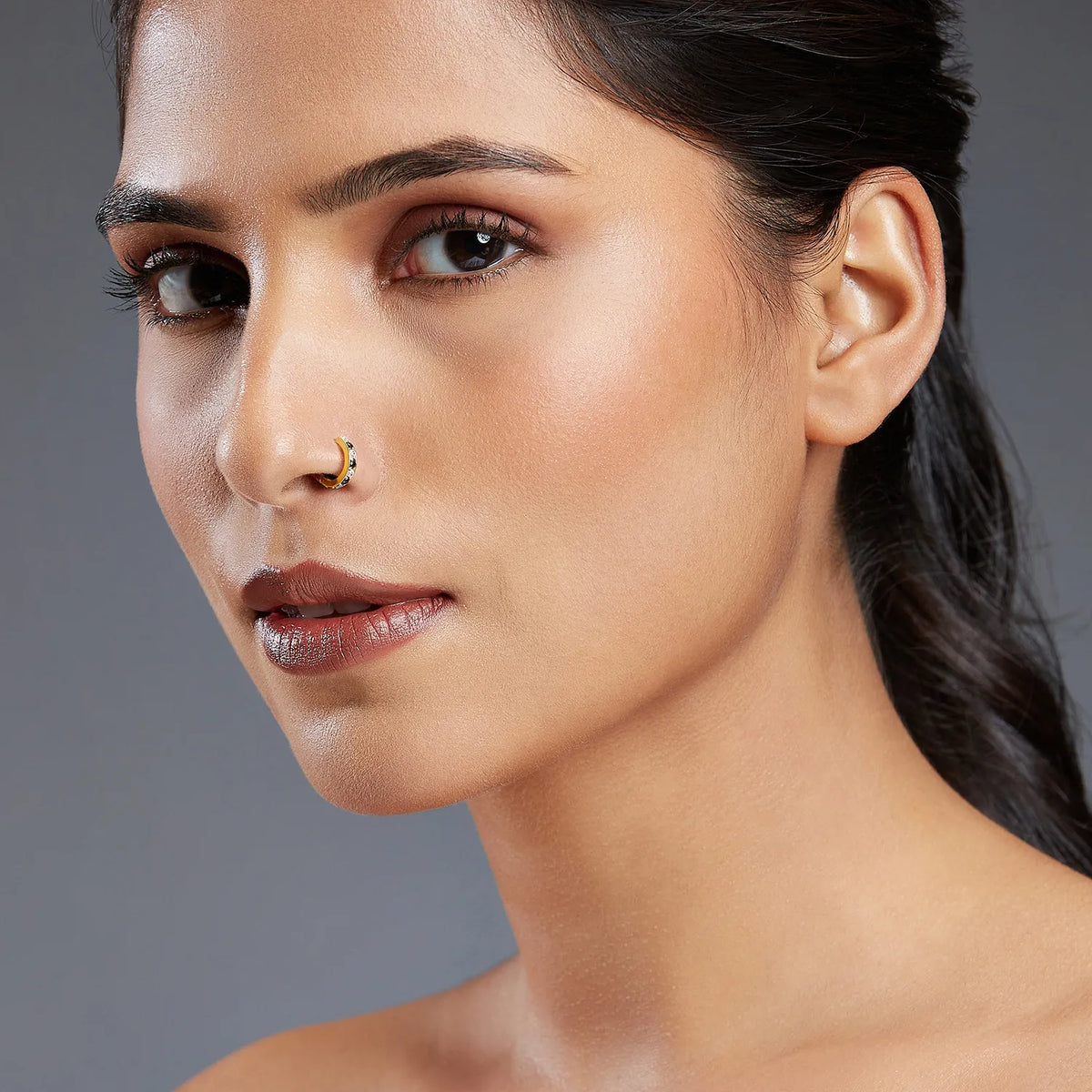 Side profile of a woman wearing a minimalist 18K gold hoop nose ring showcasing an elegant everyday look