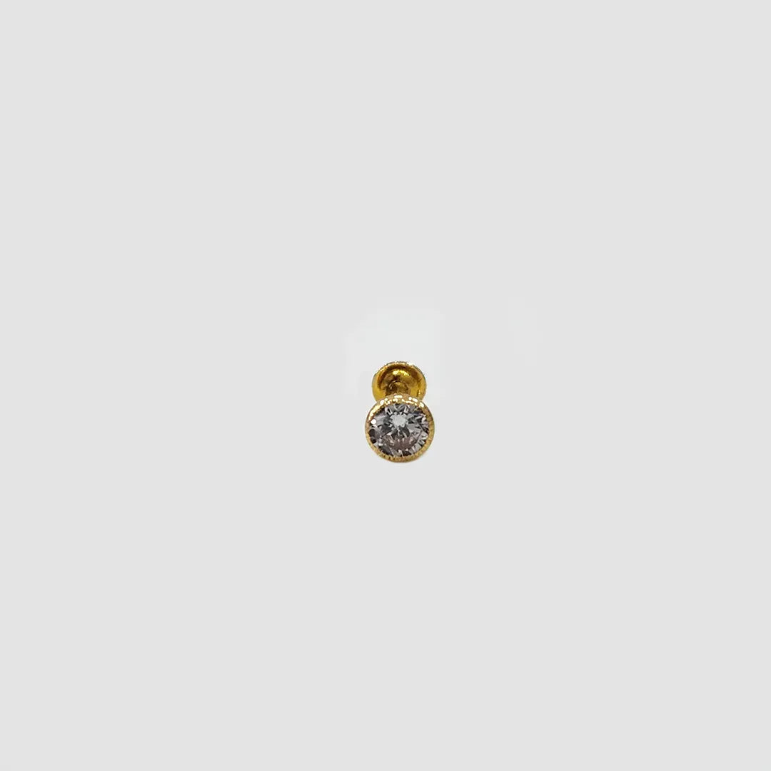 Side angle view of gold stone nose pin with clear gemstone