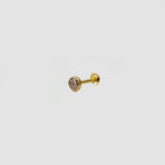 Gold stone nose pin with pink gemstone placed on light surface