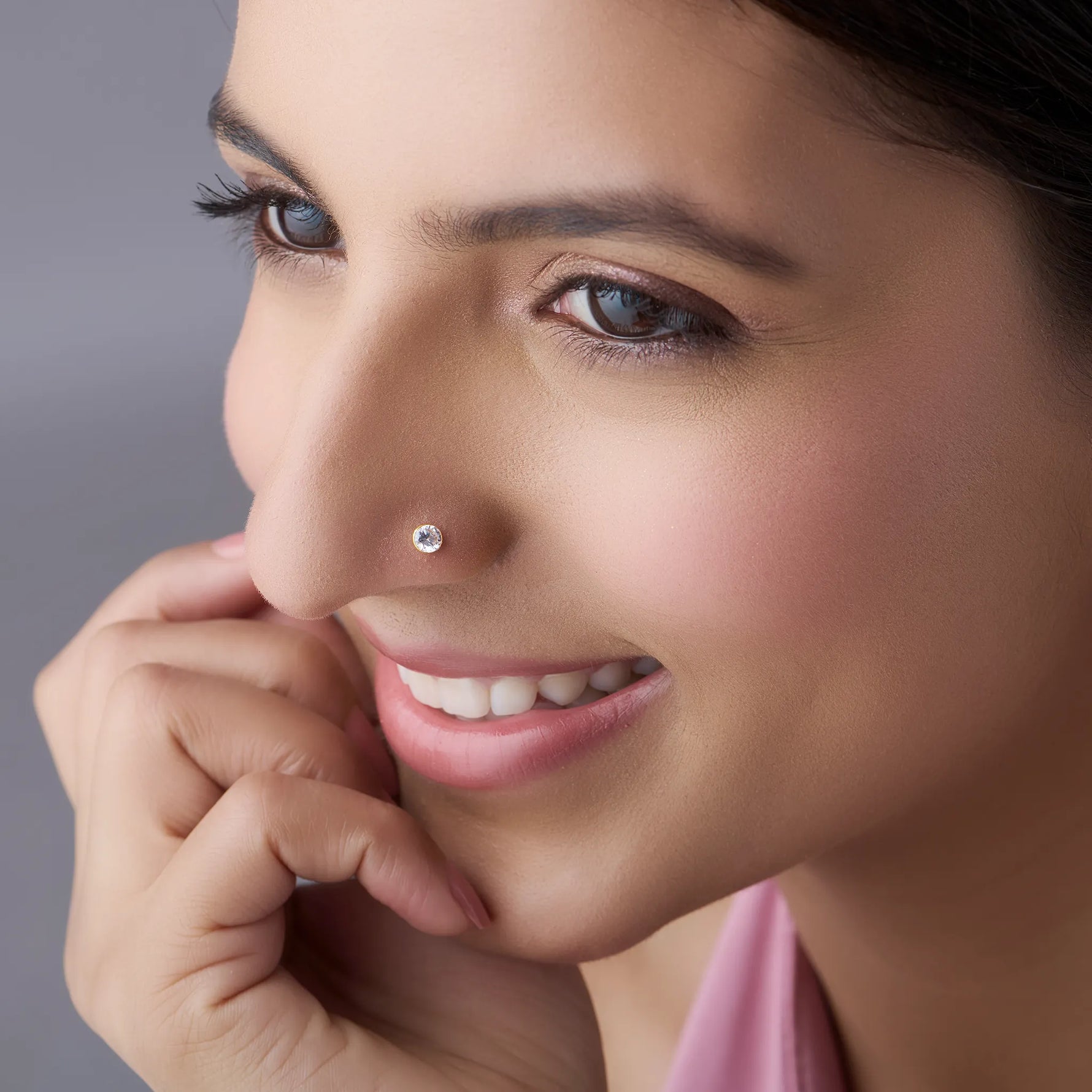 Model wearing gold stone nose pin with clear gemstone
