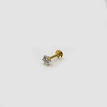Side angle view of white stone nose pin in gold on light background