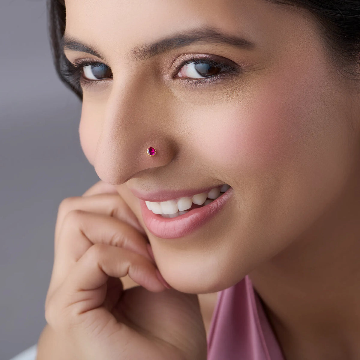 Model wearing gold stone nose pin with pink gemstone