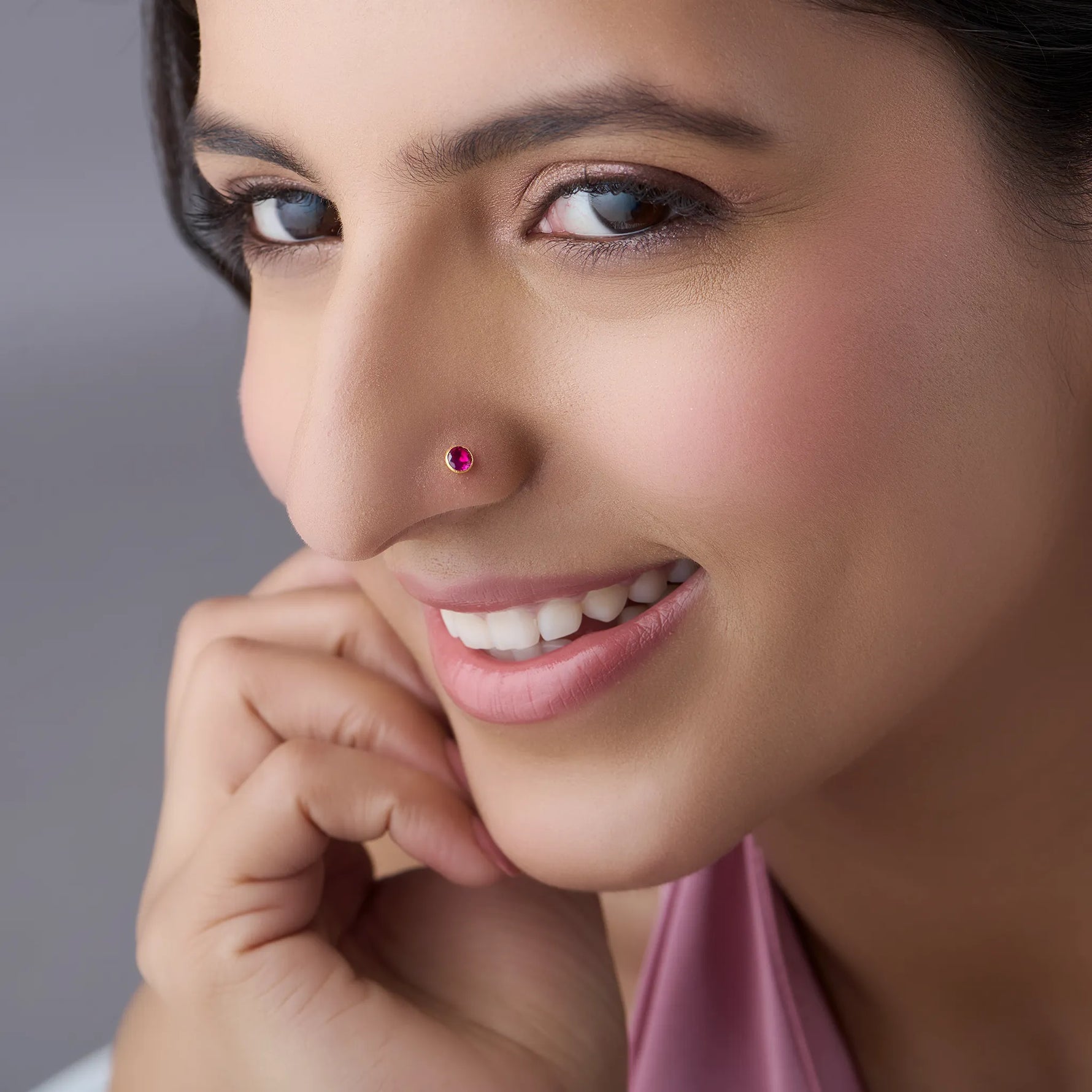 Model wearing gold stone nose pin with pink gemstone