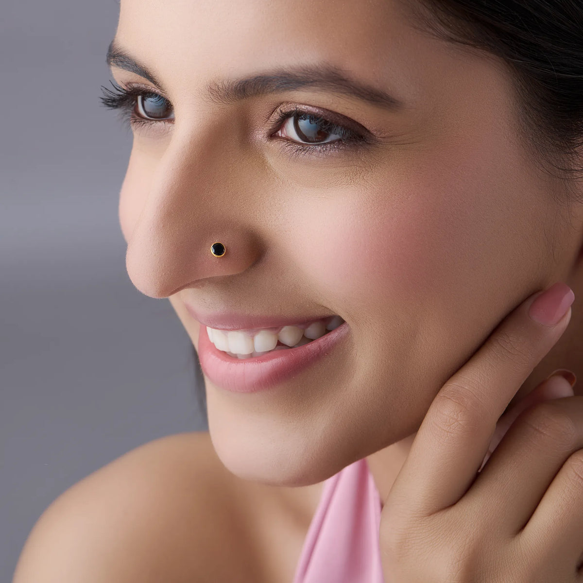 Model wearing gold stone nose pin with black gemstone