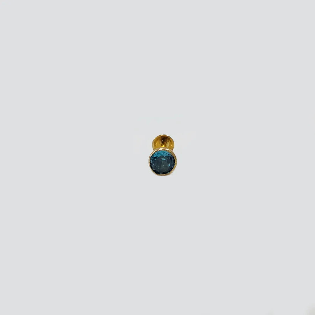 Front view of gold nose pin with round blue gemstone on white background