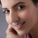 Model wearing gold stone nose pin with blue gemstone