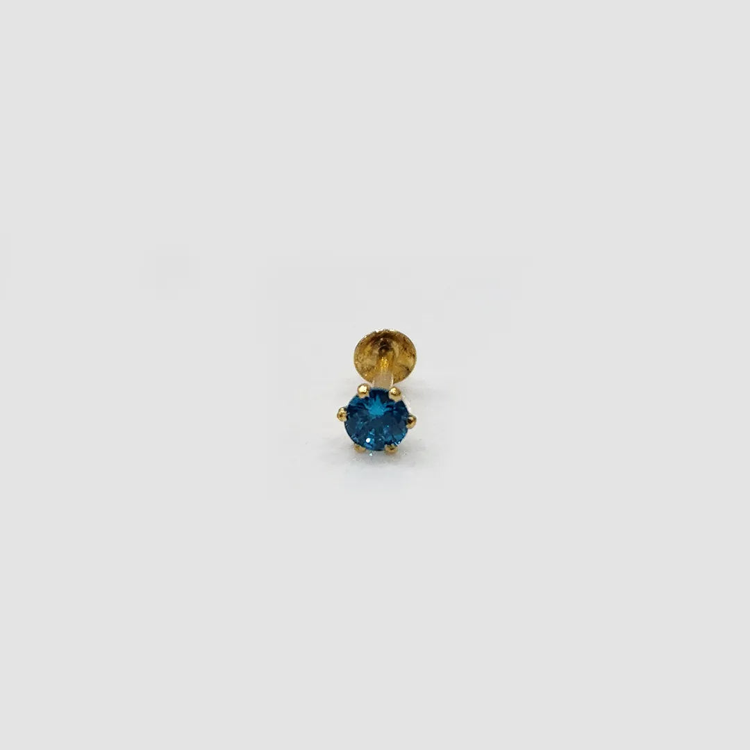 Gold stone nose pin with blue gemstone on a light background