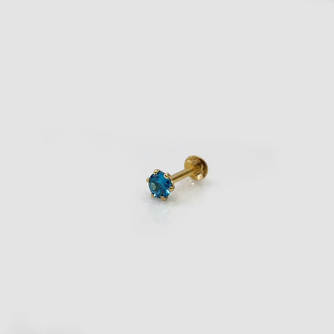 Gold stone nose pin with blue gemstone angled side view on white background