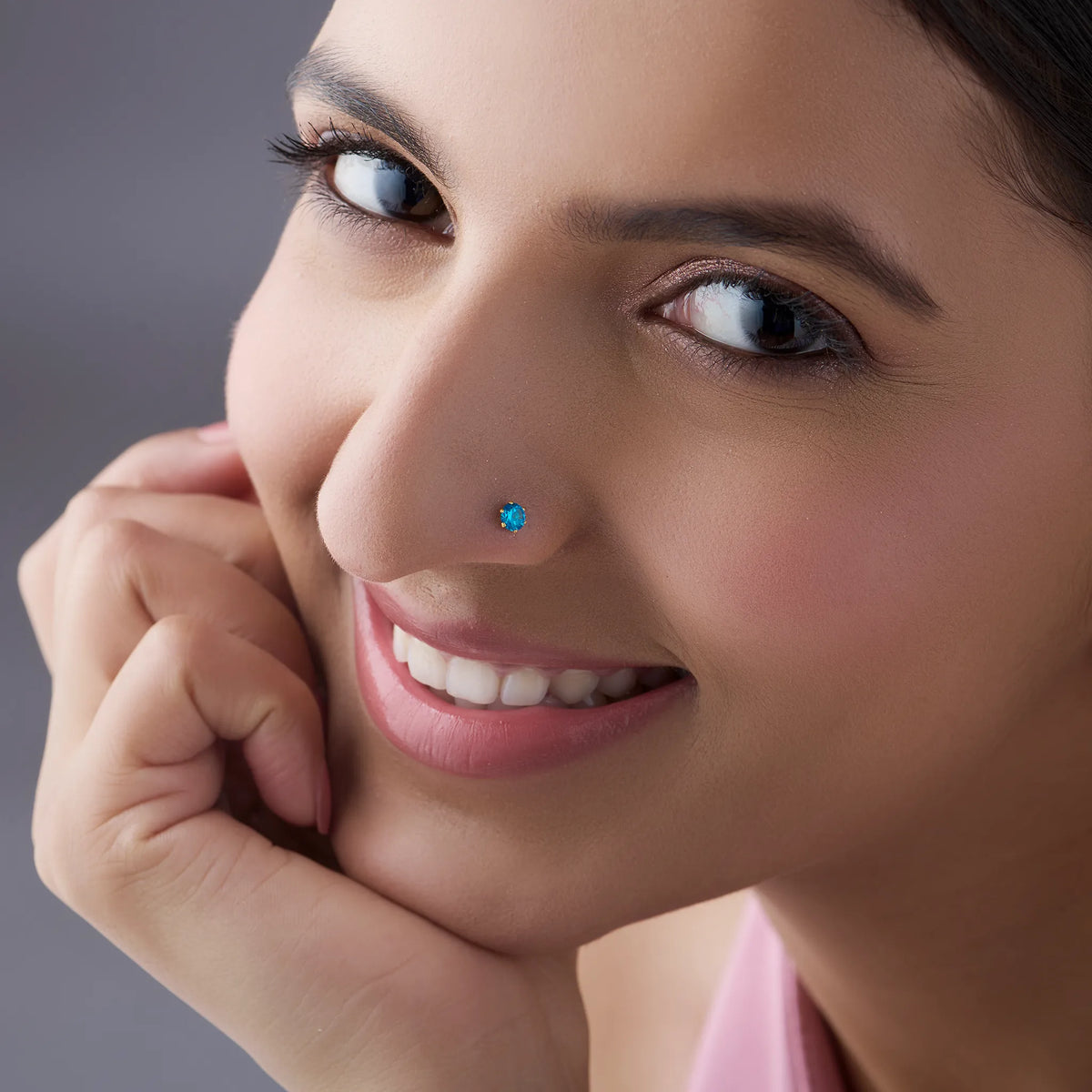 Woman smiling while wearing blue stone gold nose pin