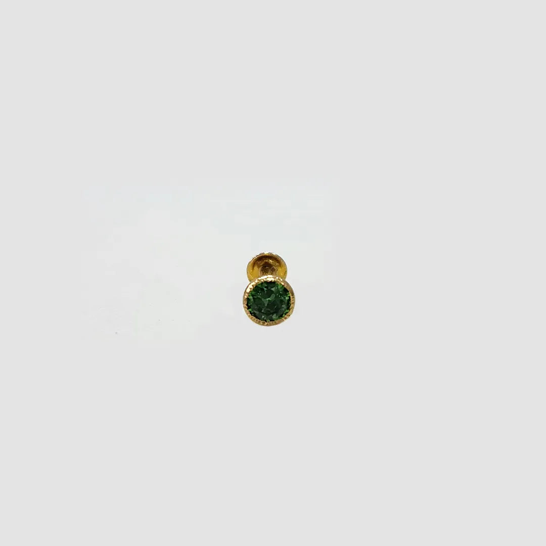 Gold stud nose pin with round green gemstone on a light gray background