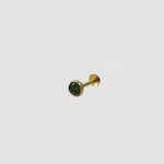 Side angle view of gold stone nose pin with green gemstone