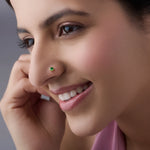 Model wearing gold stone nose pin with green gemstone