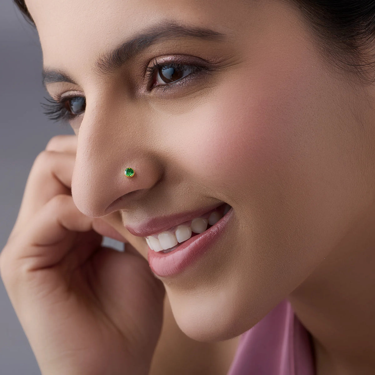 Model wearing gold stone nose pin with green gemstone
