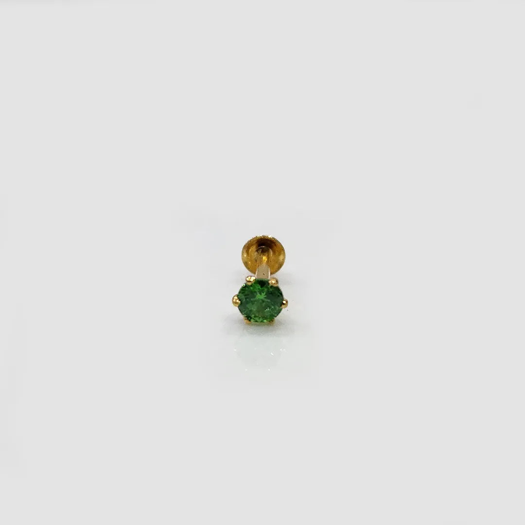 Gold stone nose pin with green gemstone on a white background
