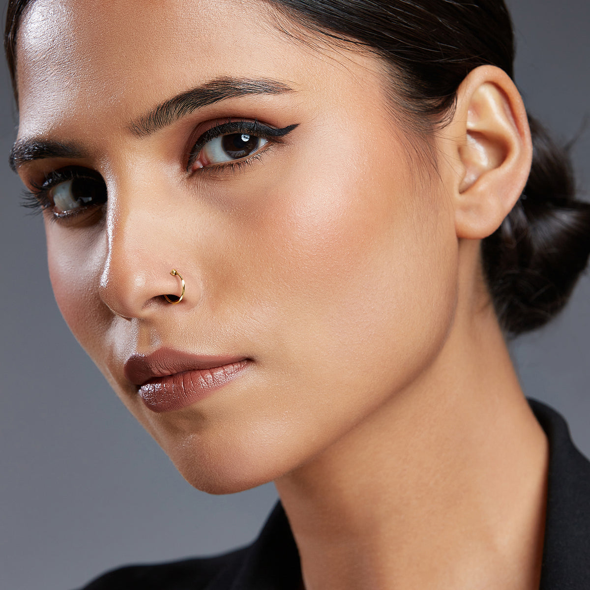 Woman wearing a minimal gold nose ring shown in a close up portrait for fit reference