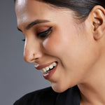 Woman smiling while wearing a simple gold nose ring captured in a soft profile view