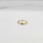 Top view of small open hoop 18K gold nose ring placed on a white background for size clarity