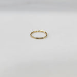 Flat lay view of a small plain gold hoop nose ring on a neutral surface showing true proportions