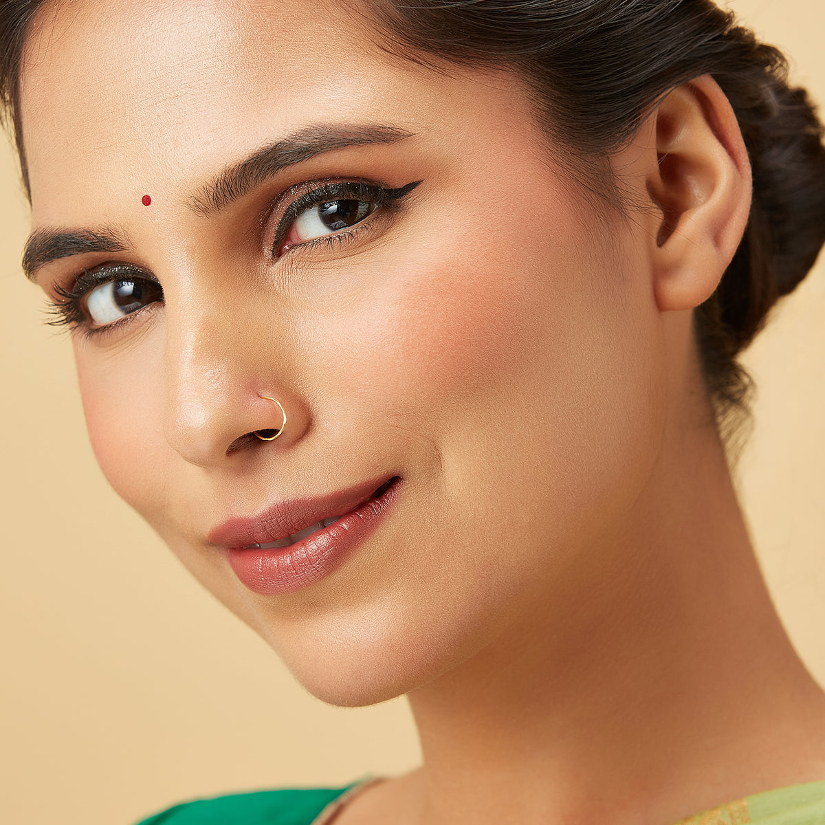 Model front facing portrait wearing a plain gold hoop nose ring for a clean elegant look
