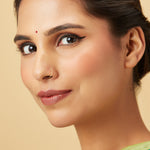 Woman wearing a minimalist gold nose ring in a close up portrait highlighting subtle everyday elegance
