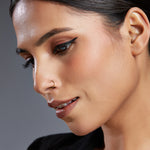 Model close up wearing a simple gold hoop nose ring highlighting natural styling