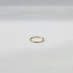 Top view of small plain gold hoop nose ring placed flat on a light grey surface to show actual size