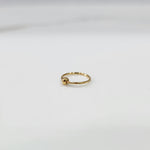 Flat lay view of petite open hoop gold nose ring on a white surface emphasizing its lightweight size