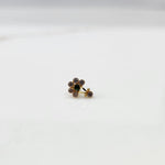 Front view of gold ring featuring clear floral gemstones with green center and drop pendant