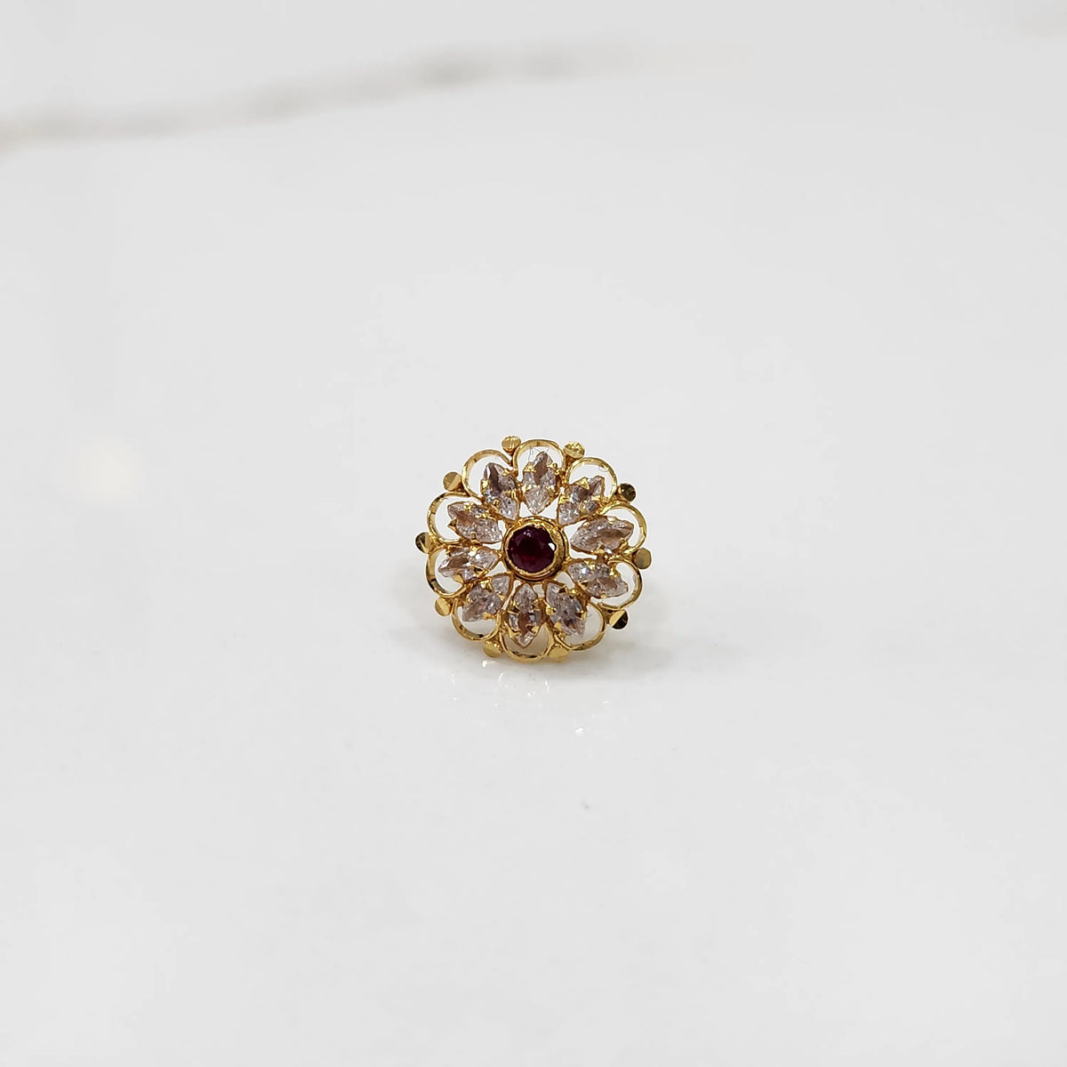 Antique-style gold ring featuring clear-toned stones with a ruby center